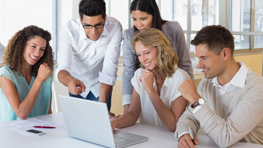 Casual smiling business team having a meeting using laptop