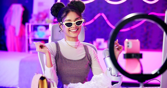 Influencer, neon and girl with microphone for fashion podcast, live streaming and broadcast at night. Content creation, light and happy woman for social media, online audience and talk show in home