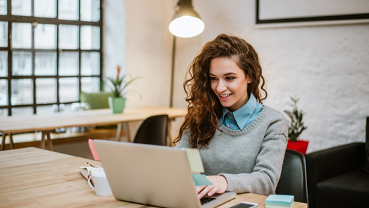 Successful young woman in modern office working on laptop.